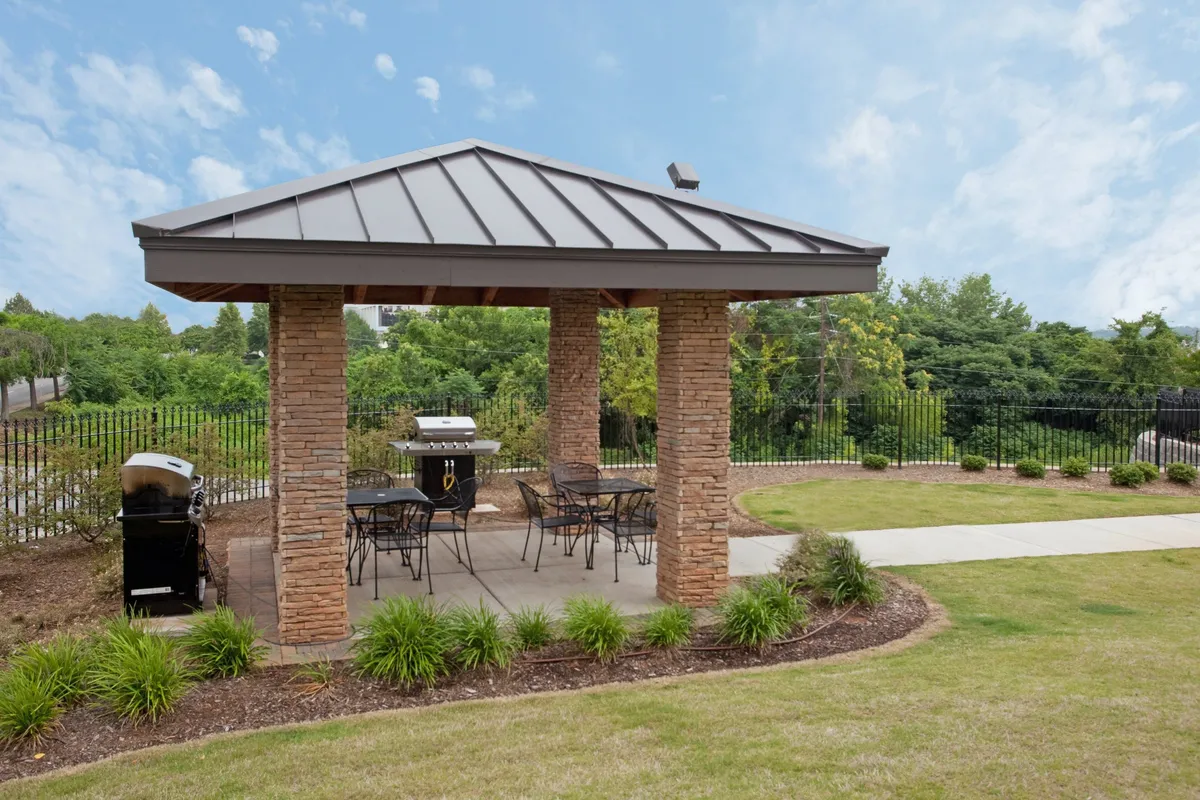 An inviting outdoor seating area featuring a grill, ample chairs, and a beautifully landscaped garden. The space exudes a casual, friendly atmosphere perfect for family barbecues and gatherings after a day of exploring local attractions.