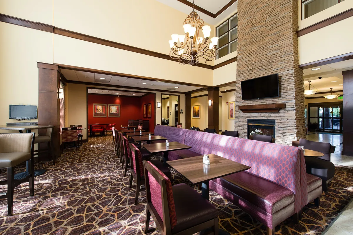 Inviting interior lounge with a chandelier, fireplace, comfortable seating area, and decorative artwork. The environment is well-suited for both informal business meetings and relaxing after a workday.